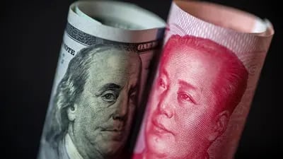 Un billete de cien dólares de EE.UU. se encuentra junto a un billete chino de cien yuanes sobre un fondo negro en esta fotografía arreglada en Hong Kong, China. Fotógrafo: Paul Yeung/Bloomberg