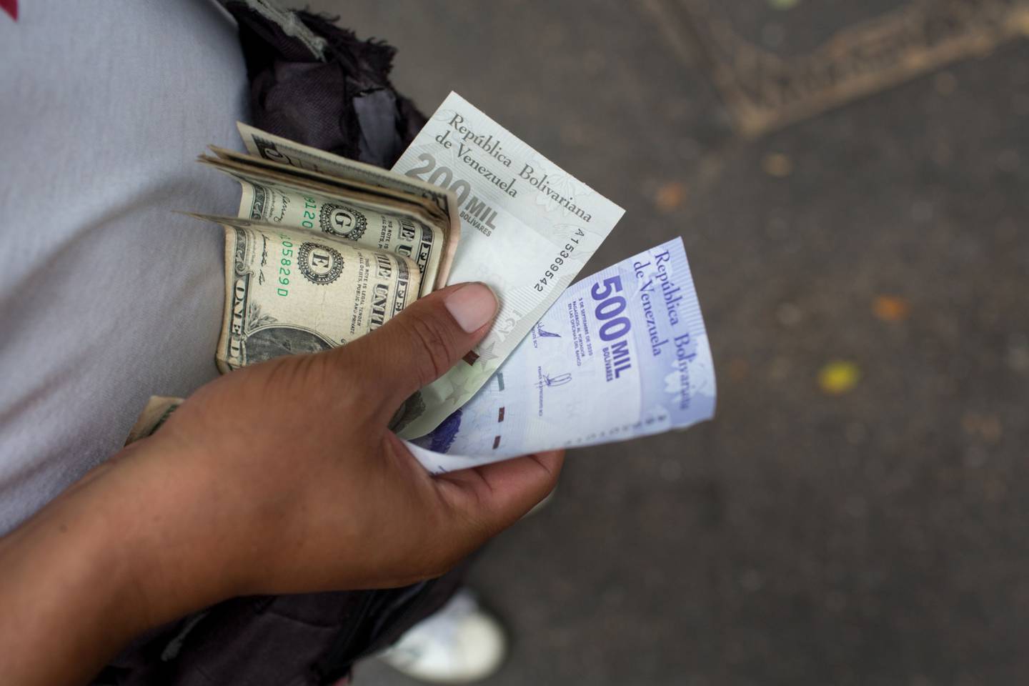 Un trabajador de autobús tiene dólares estadounidenses y billetes nuevos de 200.000 y 500.000 bolívares en una parada de autobús en Caracas, Venezuela, el lunes 15 de marzo de 2021. Fotógrafo: Manaure Quintero / Bloomberg