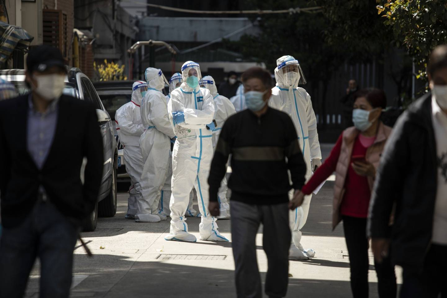 rabajadores con equipo de protección personal (EPP) vigilan mientras los residentes hacen cola para una prueba de Covid-19 en un barrio bloqueado en Shanghai, China, el lunes 4 de abril de 2022