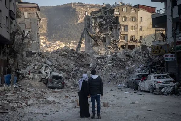 Um casal observa prédios destruídos em Hatay, na Turquia, em 19 de fevereiro