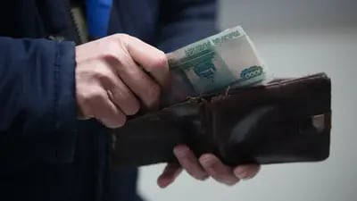 Un cliente guarda billetes de 1000 rublos en una billetera dentro de una tienda de hipermercado Magnit PJSC en Moscú, Rusia, el miércoles 28 de febrero de 2018.