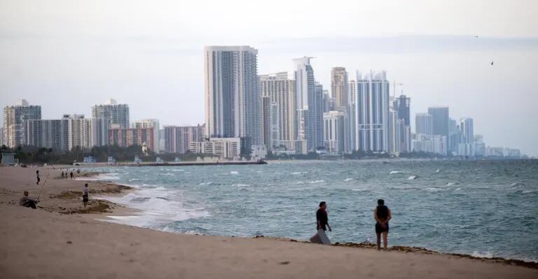 Un grupo de personas se encuentra en la orilla frente al horizonte de Miami Beach, Florida, Estados Unidodfd