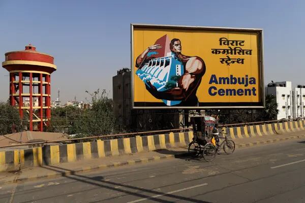 Una persona pasa frente a una valla publicitaria de Abuja Cements Ltd. en una carretera de Patna, Bihar, India, el jueves 25 de febrero de 2021.