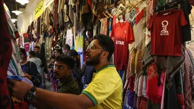 Turistas miran camisetas de fútbol a la venta en Souk Waqif en Doha, Qatar.