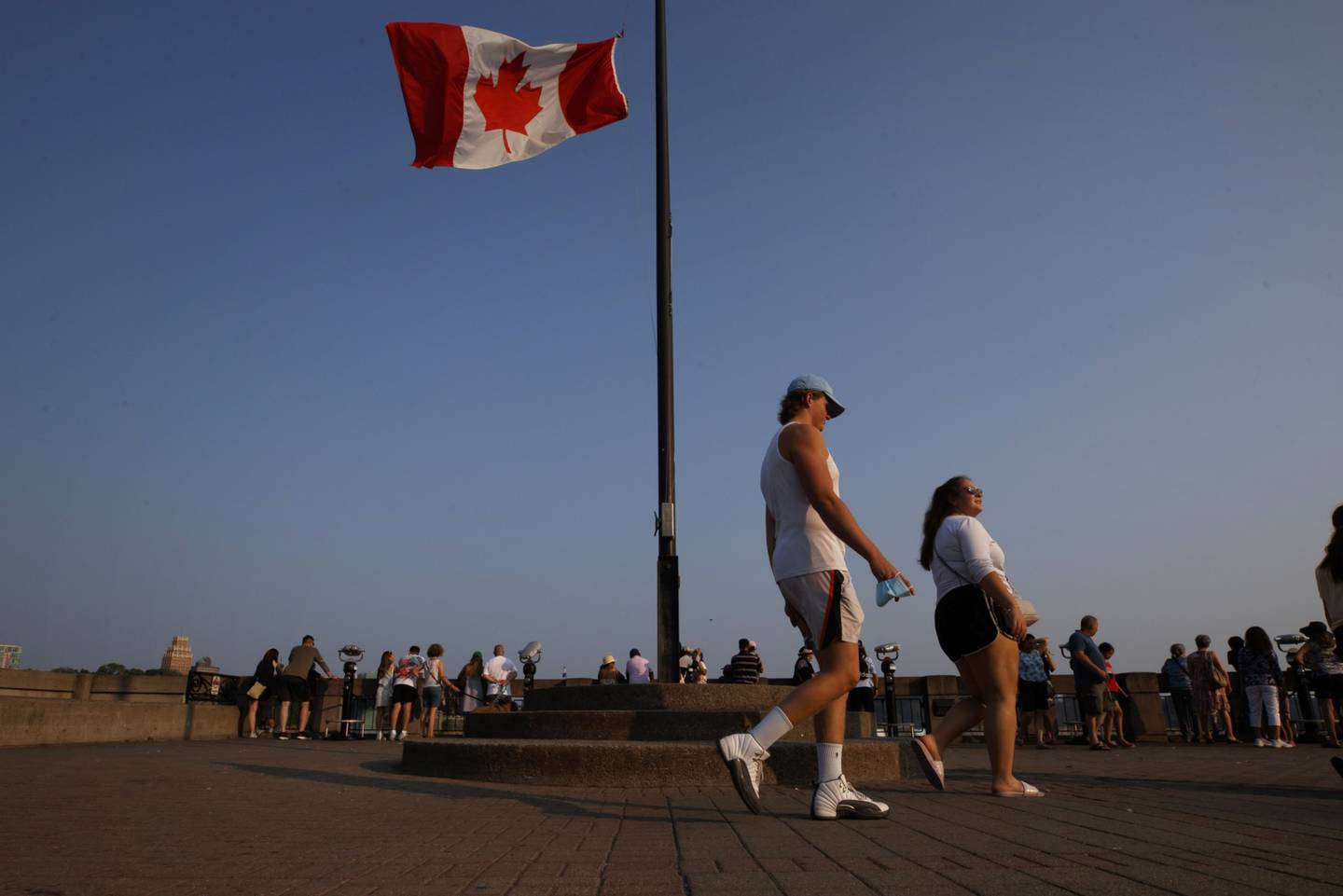 Una bandera de Canadá ondea mientras los turistas visitan las cataratas del Niágara, Ontario, Canadá, el lunes 9 de agosto de 2021.dfd