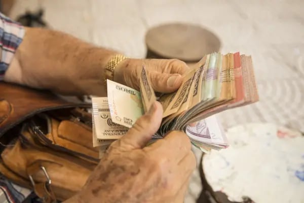 Un cambista cuenta billetes guaraníes en Asunción, Paraguay, el jueves 23 de diciembre de 2021.