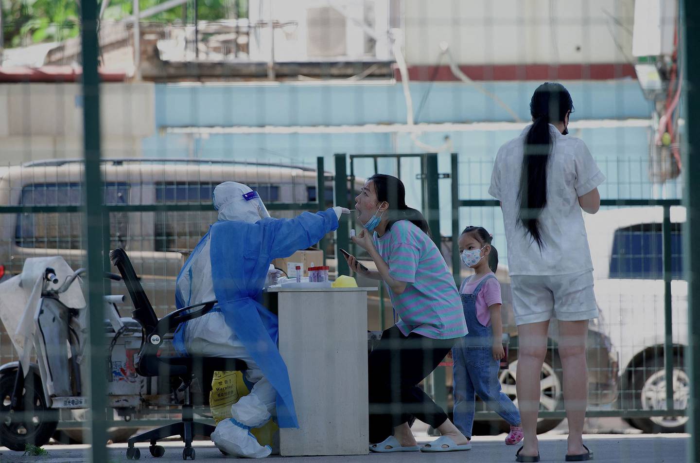 Un trabajador de la salud recibe una muestra de hisopo de una mujer dentro de un área residencial cerrada con vallas bajo confinamiento debido a las restricciones por Covid-19 en Pekín el 26 de mayo de 2022.  Fotógrafo: Noel Celis/AFP/Getty Images