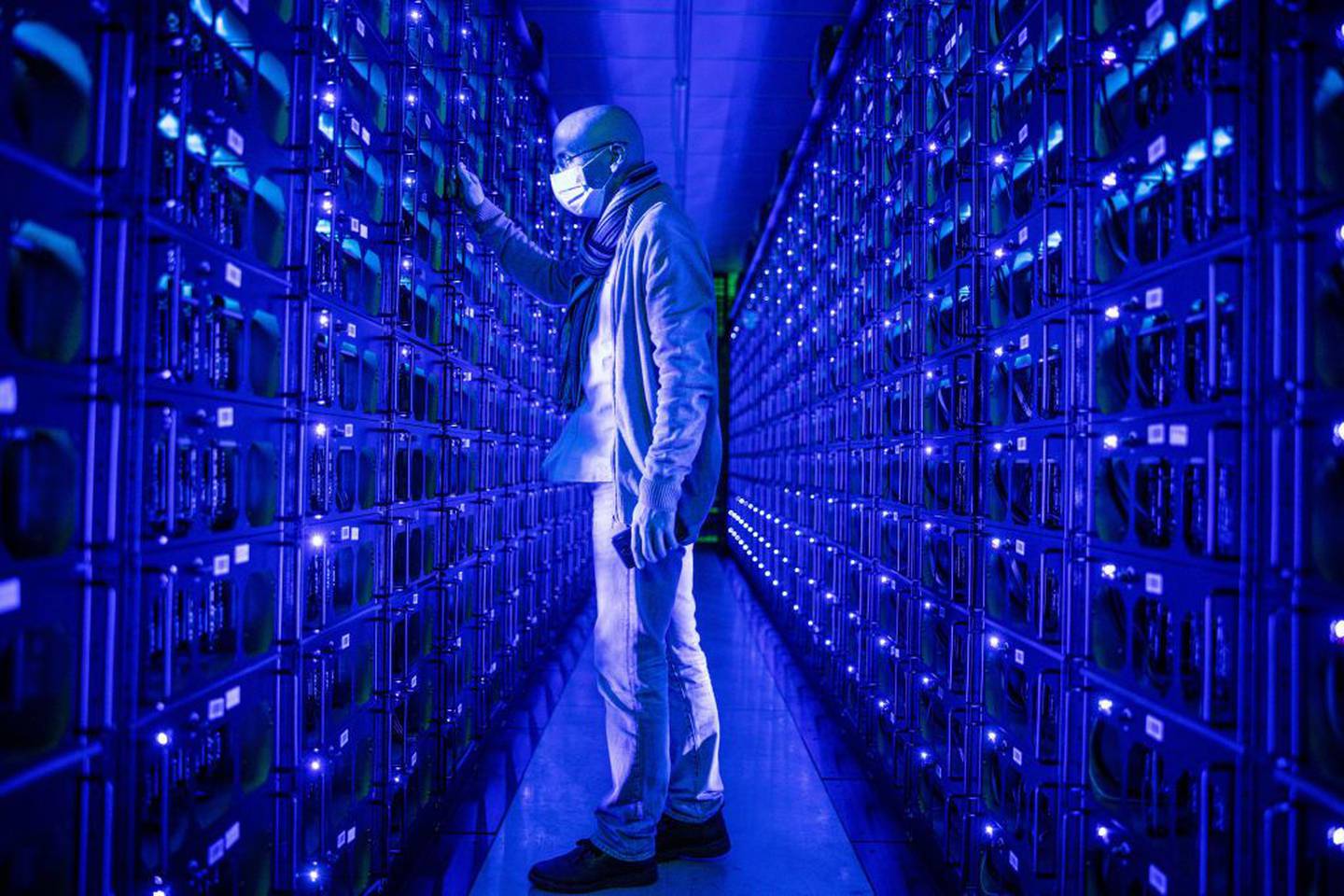 An employee wearing a protective face mask inspects mining rigs mining the Ethereum and Zilliqa cryptocurrencies at the Evobits crypto farm in Cluj-Napoca, Romania, on Wednesday, Jan. 22, 2021.