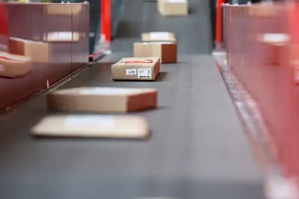 Paquetes y cajas se mueven a lo largo de una cinta transportadora en una base de entrega postal mecanizada operada por DHL, una unidad de Deutsche Post AG, en Darmstadt, Alemania, el jueves 18 de febrero de 2016