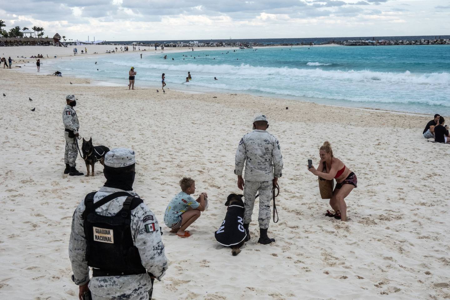 Turistas toman fotografías con miembros de la Guardia Nacional en una playa de la Zona Hotelera de Cancún, estado de Quintana Roo, México, el jueves 2 de diciembre de 2021.