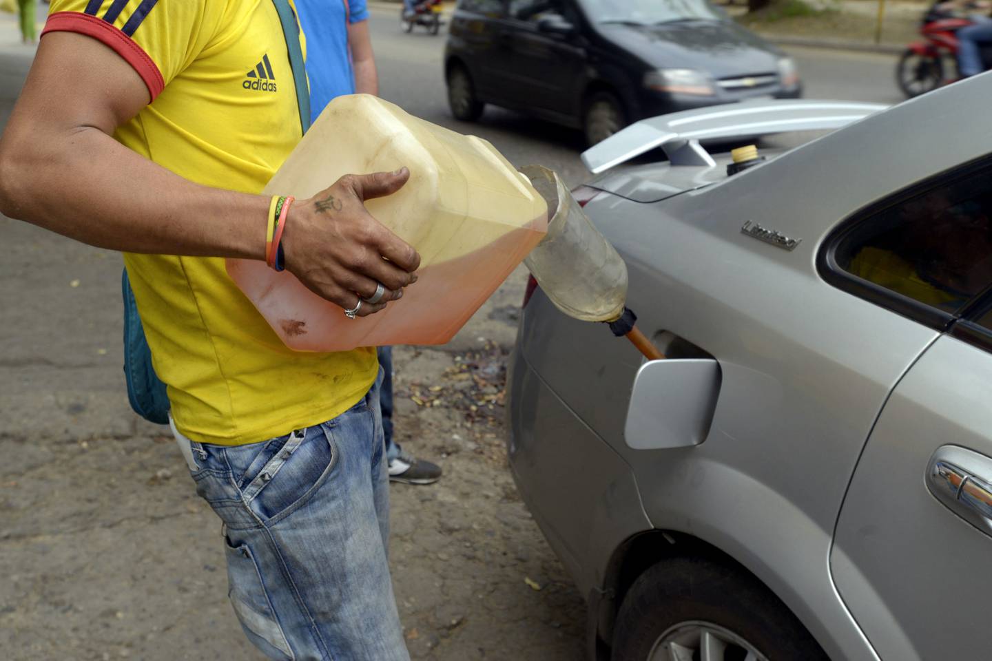 Un hombre vierte gasolina del mercado negro en el coche de un cliente en la calle en Cúcuta, Colombia, el martes 24 de febrero de 2015.dfd