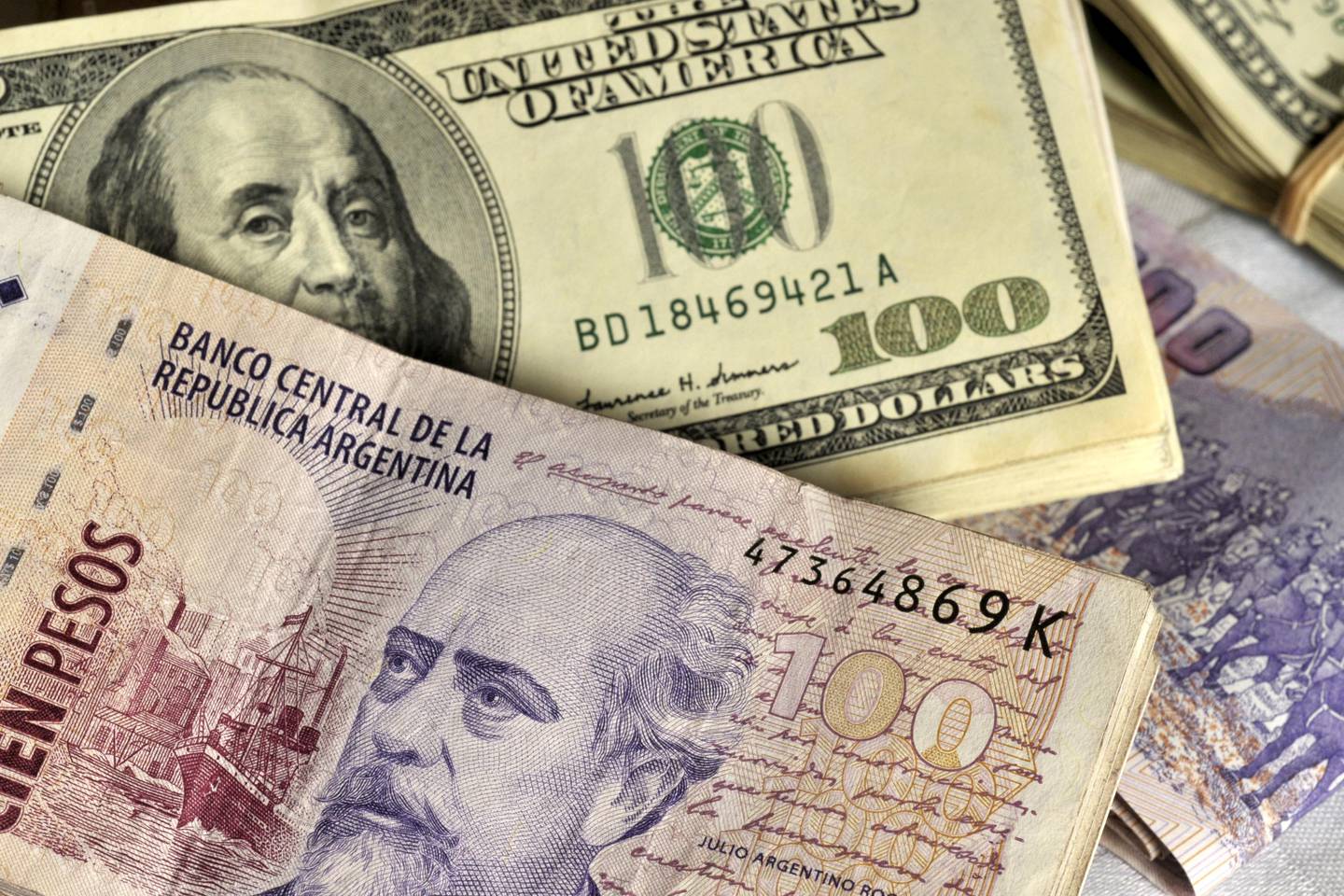 Fajos de billetes de 100 pesos argentinos y billetes de US$100.Fotógrafo: Diego Giudice/Bloomberg