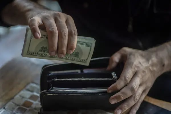 Una persona con billetes de dólar estadounidense y un monedero.