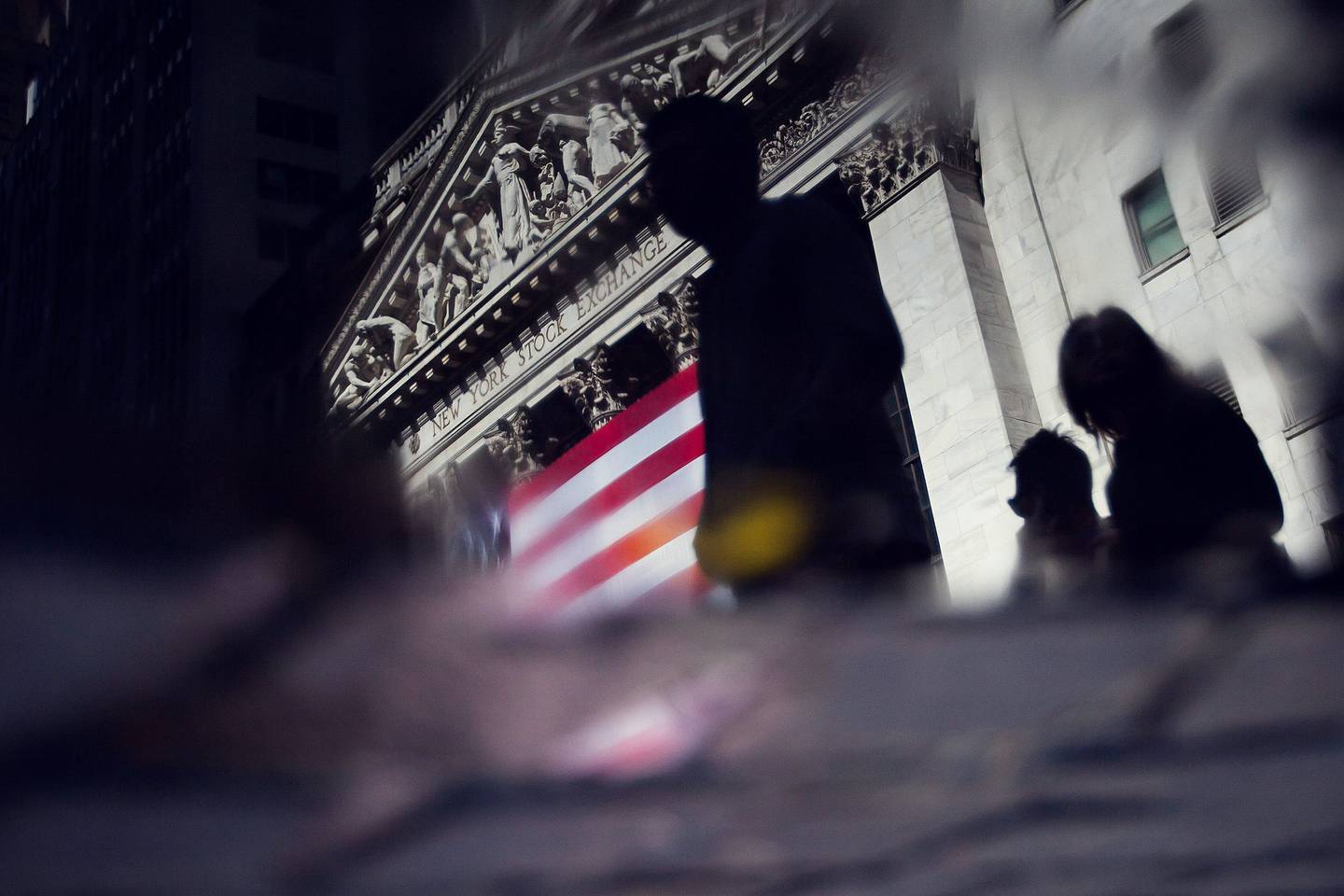 Las siluetas de los peatones se ven en un charco frente a la Bolsa de Nueva York