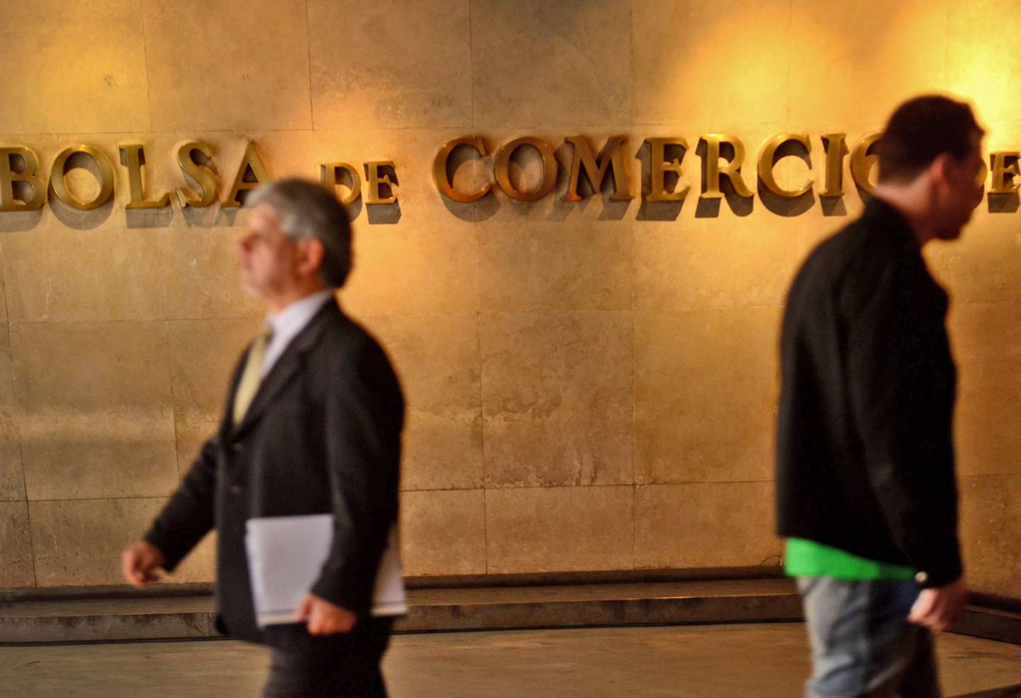 People pass in front of the entrance sign to the Buenos Aires Stock Exchange in Buenos Aires, Argentina, on Tuesday, Oct. 18, 2011. Photographer: Diego Giudice/Bloomberg