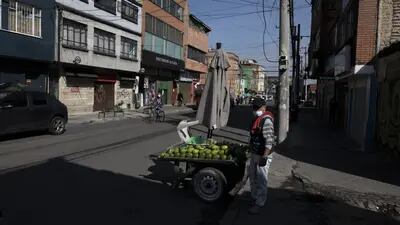 Un vendedor ambulante junto a tiendas cerradas temporalmente debido a una medida para contener la pandemia de covid-19 en Bogotá, Colombia, el sábado 25 de abril de 2021.