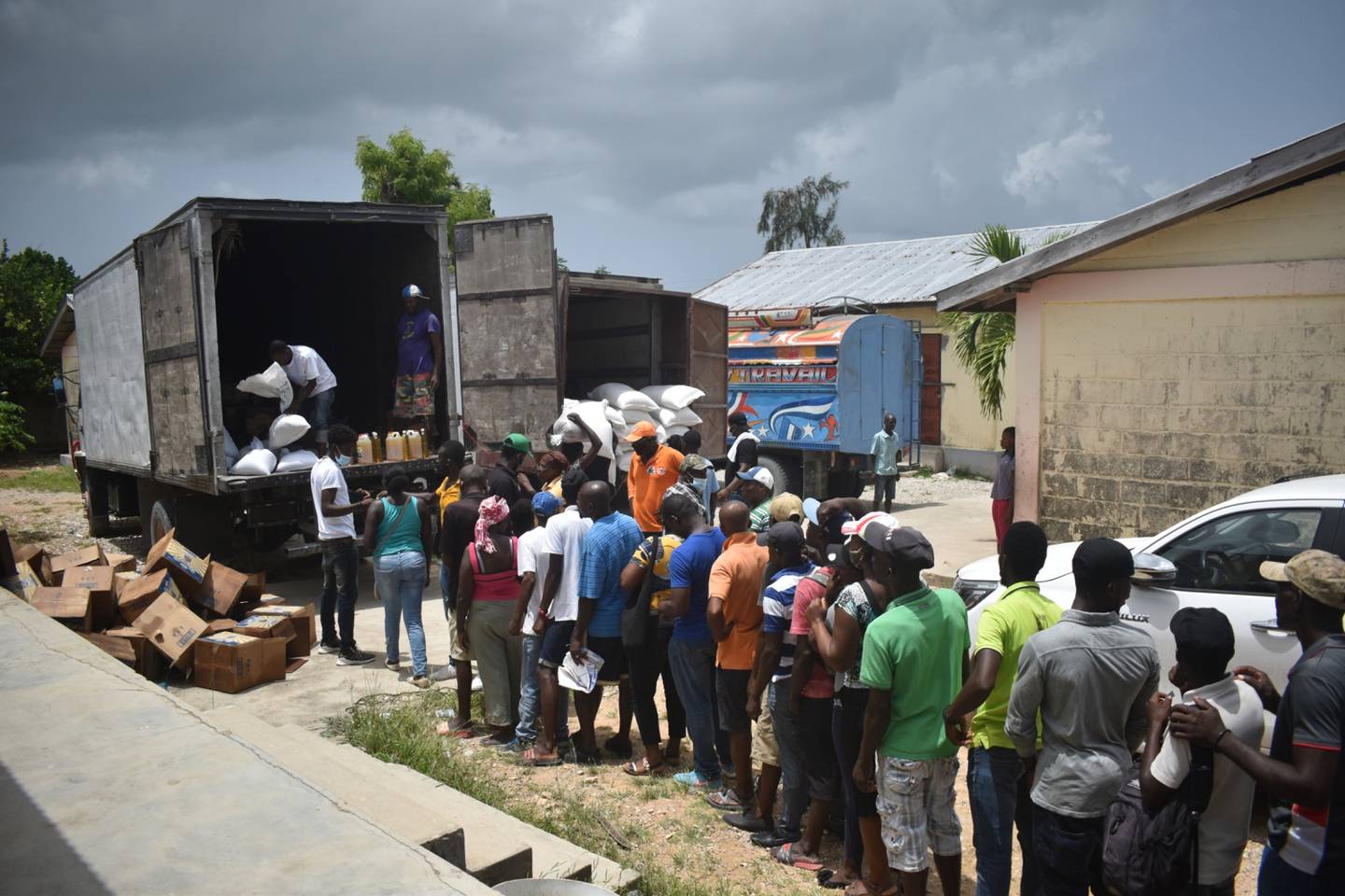 Residentes de Haití esperan en fila para recibir bolsas de arroz y aceite de cocina.