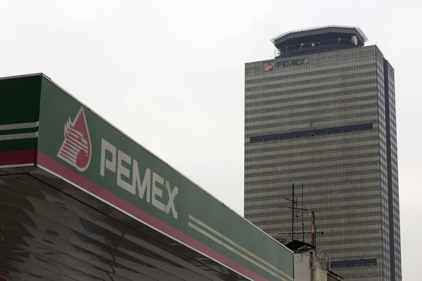 A Petroleos Mexicanos (Pemex) gas station, lower left, stands near the state-run oil company's headquarters building in Mexico City, Mexico, on Friday, March 6, 2015. Oil contracts worth more than $20 million will be open to public auction to encourage international participation as Mexico's invites foreign investment following the end of Pemex's production monopoly, according to a document published in Mexico's official gazette. Photographer: Susana Gonzalez/Bloomberg