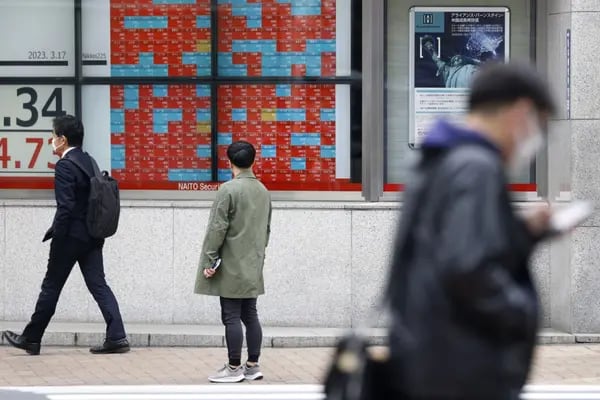 Peatones frente a una pizarra electrónica de valores fuera de una firma de valores en Tokio, Japón, el viernes 17 de marzo de 2023.