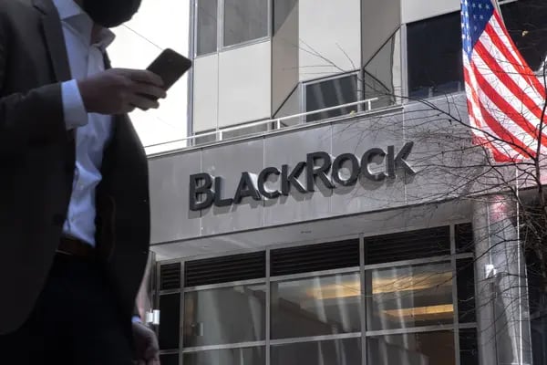 Un peatón  sosteniendo un móvil camina frente a las oficinas de  BlackRock Inc. en Nueva York, EE.UU.
