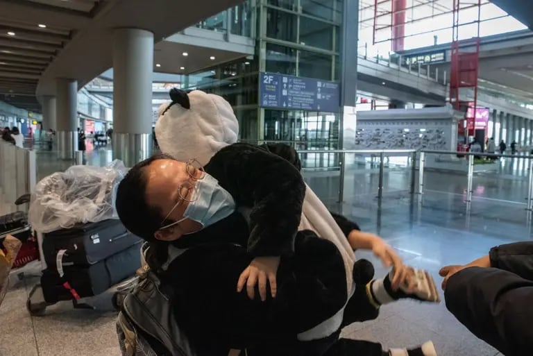 Un pariente abraza a un niño vestido con un disfraz de panda en la sala de llegadas de vuelos internacionales en Beijing, el 8 de enero de 2023.dfd