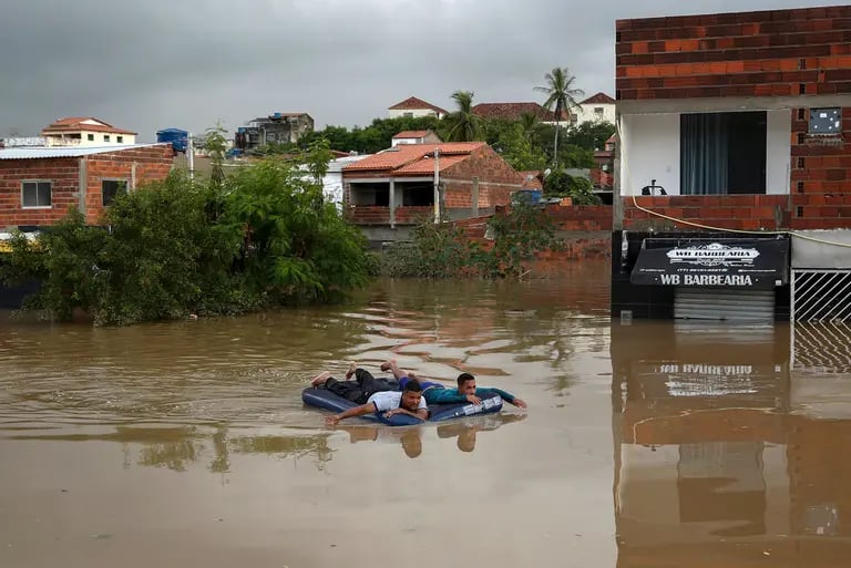 Hombres usan un colchón inflable para navegar por las calles inundadas en Itapetinga, Estado de Bahía, Brasil.Fotógrafo: Manuella Luana/AFP/Getty Imagesdfd