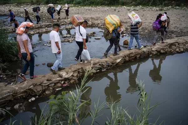 Los venezolanos cargan bolsas de suministros mientras cruzan un puente improvisado cerca de la frontera con Venezuela en Cúcuta, Colombia, el martes 26 de marzo de 2019.