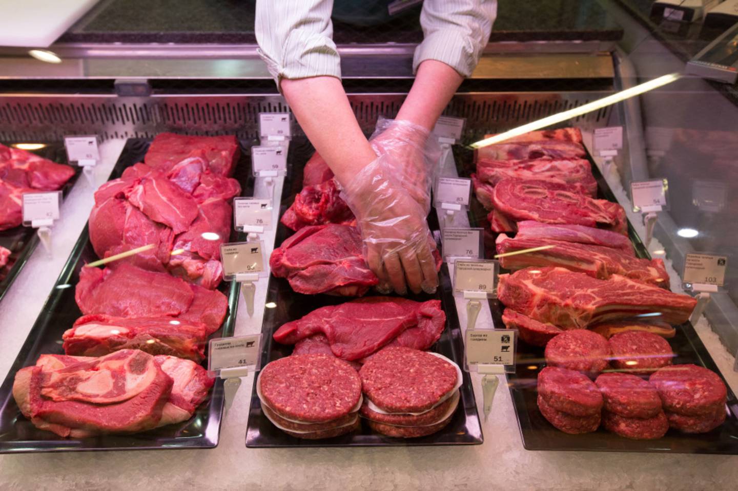 Un trabajador organiza cortes de carne para exhibirlos en un supermercado.