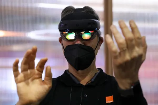 Un asistente con una máscara protectora y unas gafas HoloLens 2 de Microsoft Corp. HoloLens 2, participa en una experiencia de realidad virtual en el stand de Orange SA durante el segundo día del MWC Barcelona en la Fira de Barcelona, España, el martes 1 de marzo de 2022.