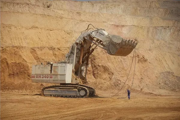 Un trabajador ayuda a operar una excavadora minera gigante de Terex Corp. durante la extracción de mineral del pozo abierto en la mina de cobre y cobalto KOV de Katanga Mining Ltd. en Kolwezi, provincia de Katanga, República Democrática del Congo, el miércoles 1 de agosto de 2012.