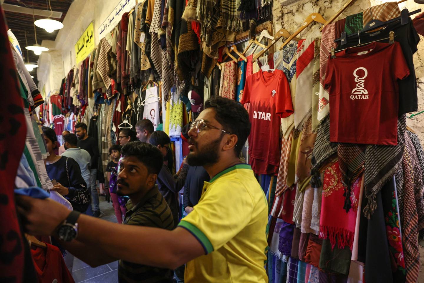 Turistas miran camisetas de fútbol a la venta en Souk Waqif en Doha, Qatar.dfd