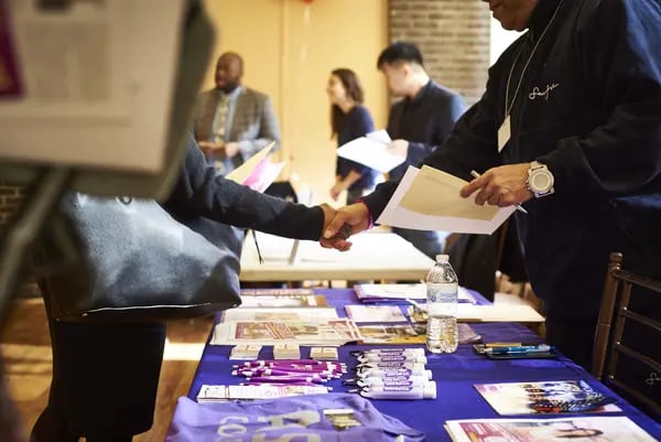 A job seeker, left, shakes hands with a representative during a Shades of Commerce Career Fair in the Brooklyn borough of New York, U.S., on Saturday, Feb. 17, 2018. The latest initial jobless claims, which correspond to the February employment survey period, fell from the previous week to a five-week low and continue to flirt with multi-decade lows.