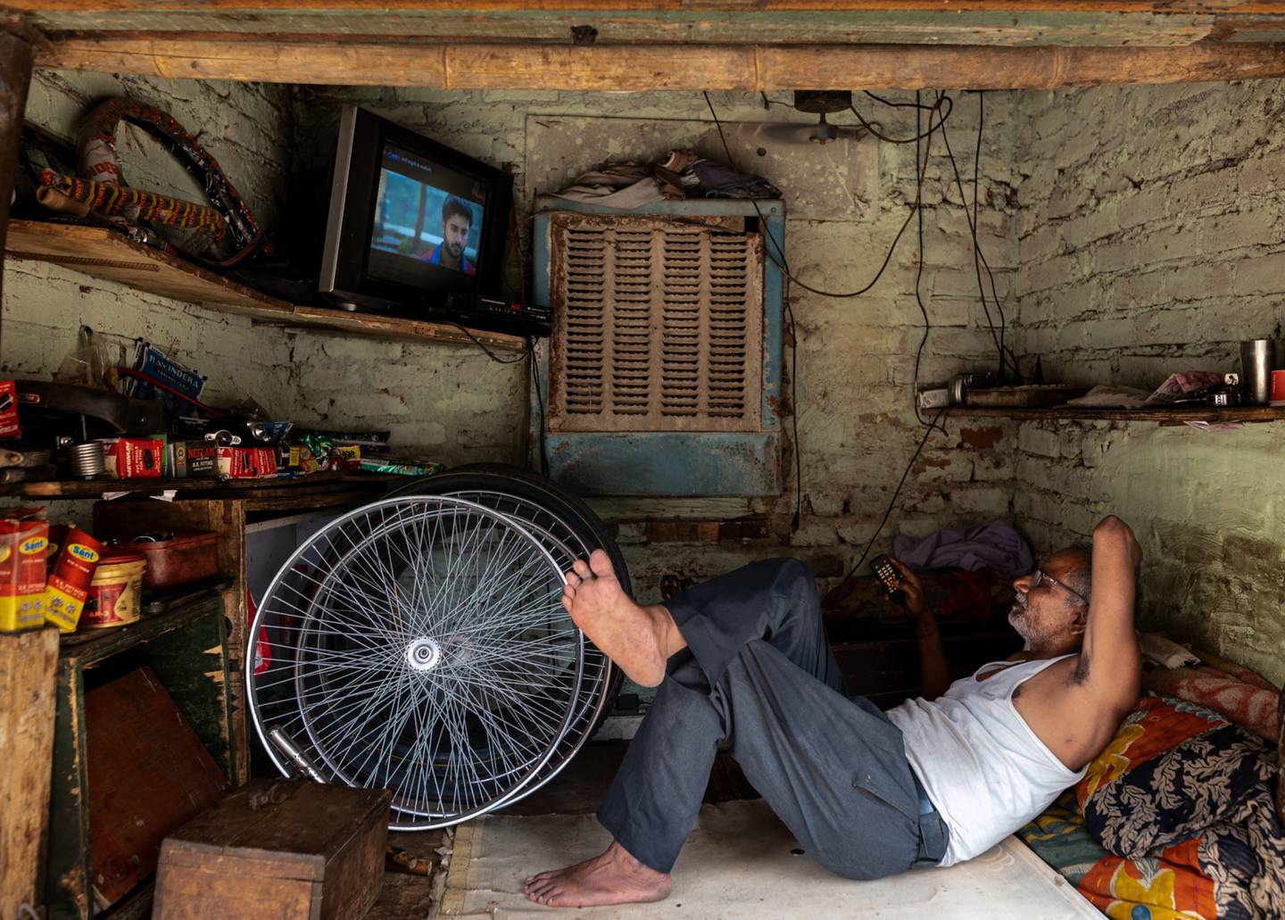 Un vendedor mira la televisión mientras descansa en el interior de un taller de reparación de bicicletas en Nueva Delhi, India, el viernes 19 de mayo de 2023. El calor extremo que asoló partes del sudeste asiático el mes pasado se debió en gran medida al cambio climático inducido por el hombre, según el análisis de un equipo de científicos. Fotógrafo: Anindito Mukherjee/Bloomberg
