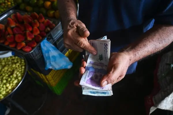 Un vendedor cuenta billetes de pesos colombianos en un mercado de Cali, Colombia. Fotógrafo: Joaquín Sarmiento/AFP/Getty Images