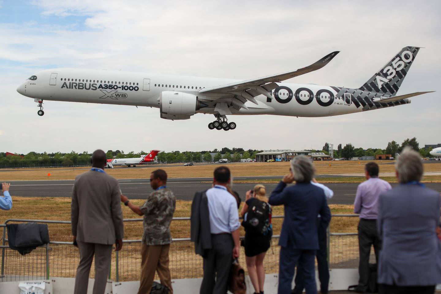 Spectators watch an Airbus SE A350-1000 aircraft land on the opening day of the Farnborough International Airshow (FIA) 2018 in Farnborough, U.K., on Monday, July 16, 2018. The air show, a biannual showcase for the aviation industry, runs until July 22.