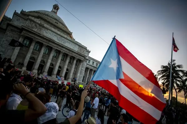 Un manifestante ondea una bandera de Puerto Rico frente al edificio del Capitolio durante una protesta contra el gobierno en San Juan, Puerto Rico, el lunes 20 de enero de 2020.