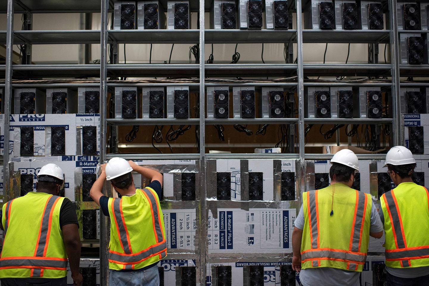 Workers install a new row of Bitcoin mining machines at the Whinstone Bitcoin mining facility in Rockdale, Texas.