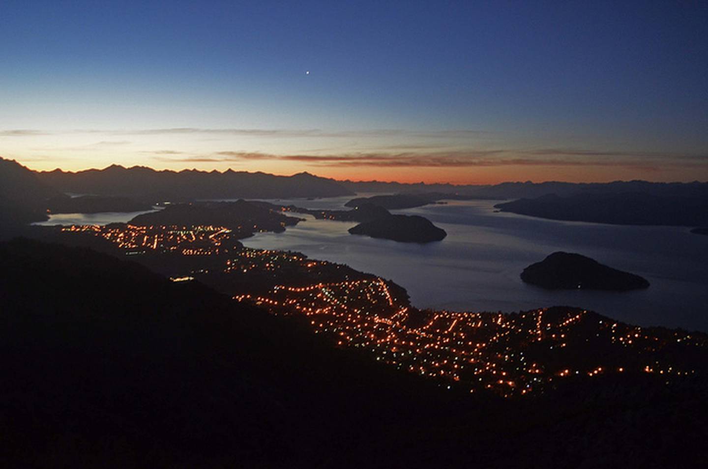 Las luces de la ciudad y el lago Nahuel Huapi, protagonista de la Patagonia argentina.