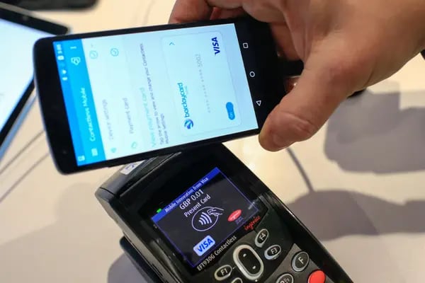 Un trabajador demuestra un sistema de pago móvil en el stand de Visa Inc. en el Congreso Mundial Móvil en Barcelona, ​​España.