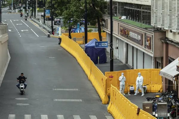 Trabalhadores desinfetantes usando equipamentos de proteção individual (EPI) atrás de barreiras durante um bloqueio devido ao Covid-19 em Xangai, China, na segunda-feira, 16 de maio de 2022.