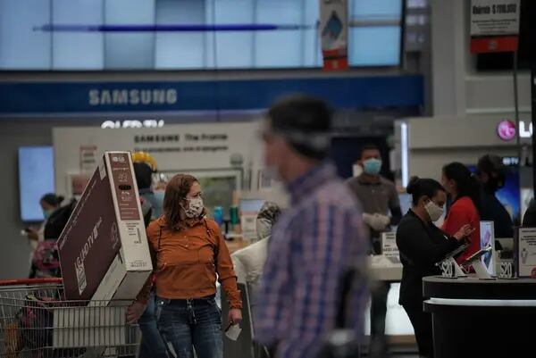 Los compradores con máscaras protectoras buscan productos electrónicos en una tienda Alkosto en Bogotá, Colombia, el viernes 19 de junio de 2020.