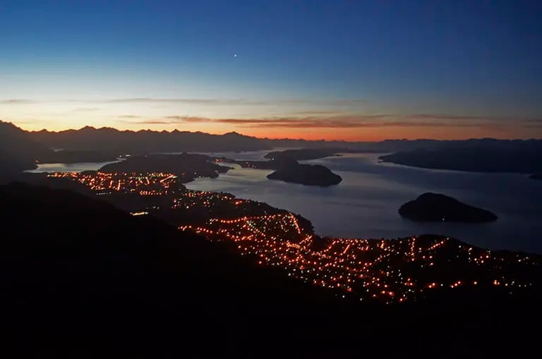 Las luces de la ciudad y el lago Nahuel Huapi, protagonista de la Patagonia argentina.dfd