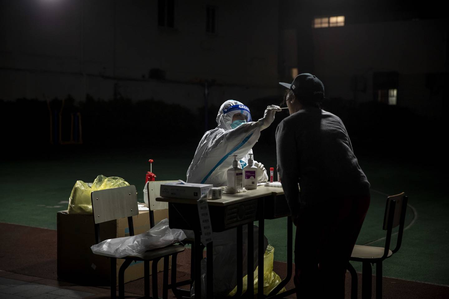 Un trabajador recoge una muestra de hisopo de un residente para una prueba de Covid-19 en un vecindario bajo cierre en Shanghai, China.