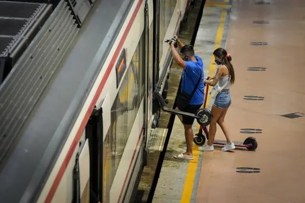 Los pasajeros que utilizan patinetes eléctricos abordan un tren en la plataforma de servicios regionales de la estación de tren de Atocha en Madrid, España, el miércoles 5 de agosto de 2020