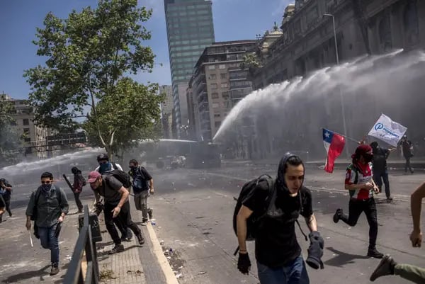 Los manifestantes huyen de un cañón de agua de la policía antidisturbios durante una protesta en la Plaza Italia en Santiago en 2019. Fotógrafo: Cristobal Olivares/Bloomberg