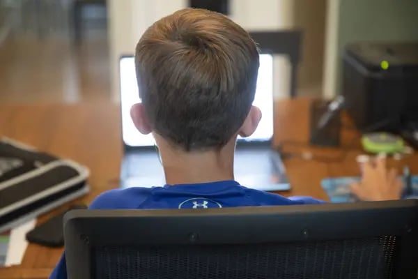 Un estudiante trabaja en su computadora portátil en casa