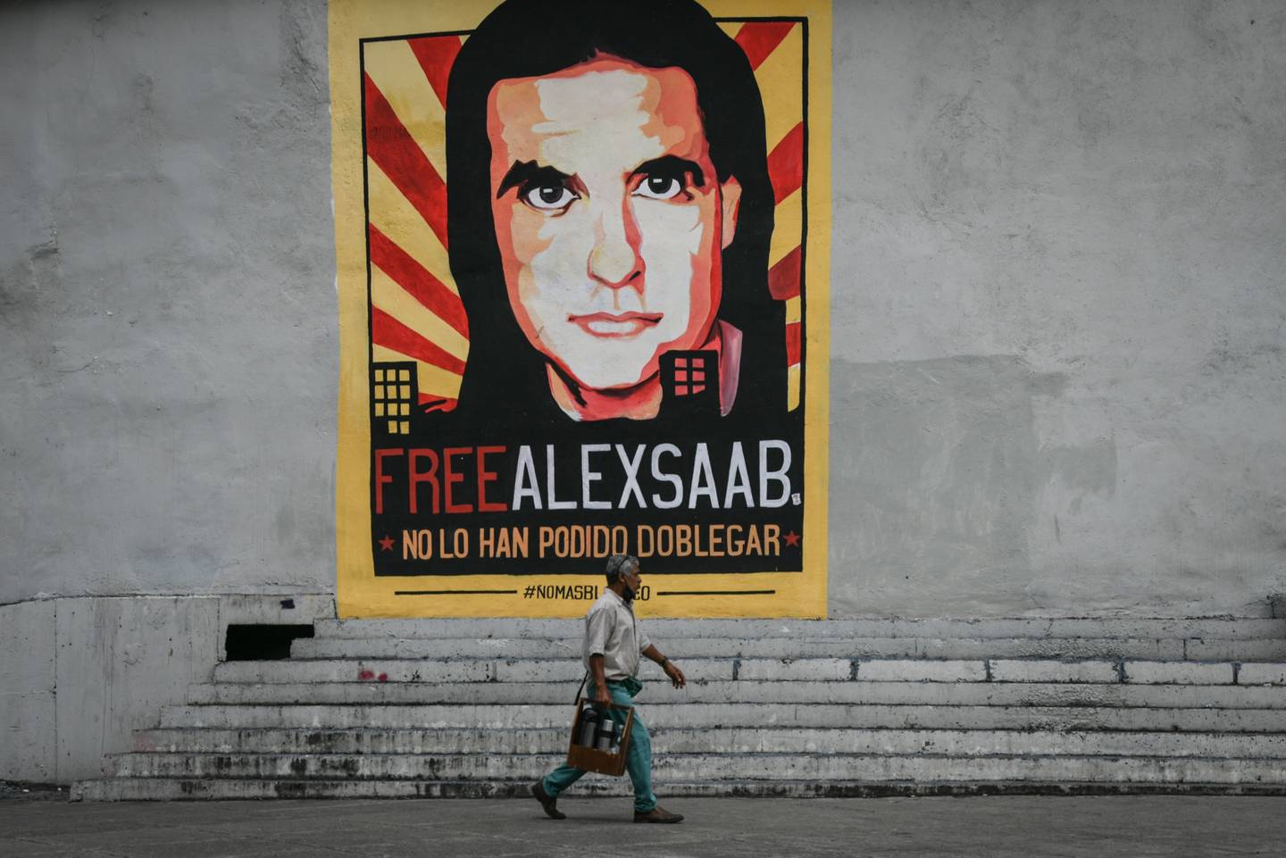 Un peatón pasa por delante de un mural de apoyo al empresario encarcelado Álex Saab en Caracas. El gobierno venezolano emprendió una campaña a su  favor, en la que le dio el cargo de diplomático y lo incluyó en la mesa de negociaciones en México.