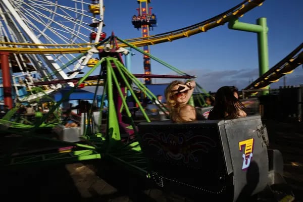 Tourists Tea Wagner, 16, left, of Austria and Jexi Keith, 16, of Costa Rica ride the Pacific Park Scrambler near the Ferris wheel on the Santa Monica Pier in Santa Monica, California, U.S., on Monday, Aug. 5, 2013. Overall U.S. tourism-related sales increased 6.8% in the second quarter of 2013 as compared to 2012. Photographer: Patrick Fallon/Bloomberg *** Local Caption *** Tea Wagner; Jexi Keith