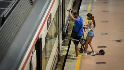 Los pasajeros que utilizan patinetes eléctricos abordan un tren en la plataforma de servicios regionales de la estación de tren de Atocha en Madrid, España, el miércoles 5 de agosto de 2020