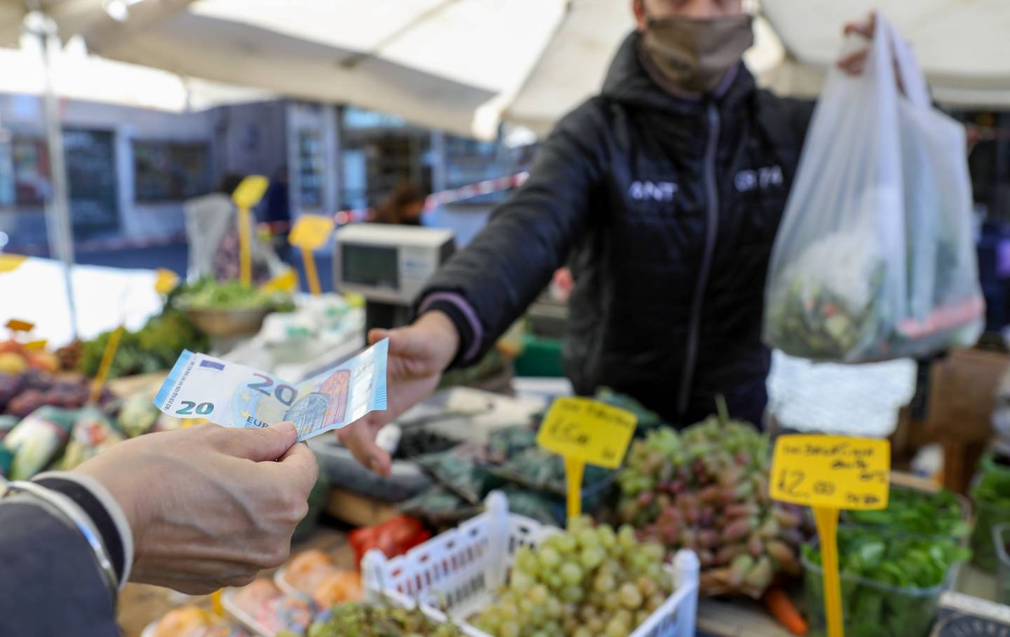 A customer hands a 20 Euro currency banknote to a vendor at a stall selling fruit and vegetables in Rome, Italy, on Thursday, Oct. 8, 2020. Italy's government reinforced measures to curb the coronavirus pandemic, including decreeing that protective masks must be worn outdoors across the country. Photographer: Alessia Pierdomenico/Bloomberg